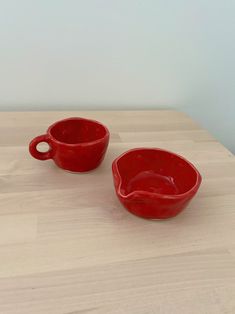 two red bowls sitting on top of a wooden table