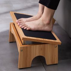 a person standing on a wooden stool with their feet resting on the top one foot