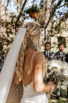 the bride is walking down the aisle with her bouquet in hand as she looks on