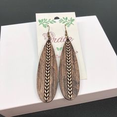 the earrings are made from wood and have an intricate design on them, which is accented with braiding