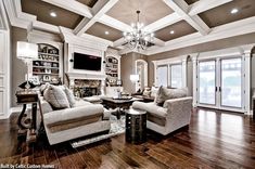 a living room filled with lots of furniture and a chandelier hanging from the ceiling