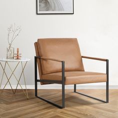 a brown leather chair sitting on top of a hard wood floor next to a table