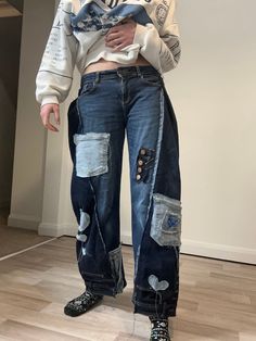 a woman standing in front of a white wall wearing ripped jeans and a hoodie