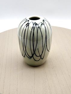 a white and black vase sitting on top of a wooden table