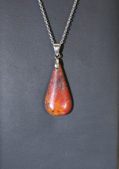 This beautiful teardrop is a fire like red and orange with hints of white and blue green in places. The stone is a Sanora sunrise chrysocolla from Mexico. This is a natural stone that's a mixture of different minerals. The stone is about 32x16 mm. The included stainless steel chain is 20 inches in length. In the global market we encourage you to shop local by supporting artists and small businesses who cut stones safely and ethically within the U.S.A. All of our stones and fordite are made by us Amber Teardrop Cabochon Necklace, Rust Teardrop Handmade Jewelry, Teardrop Agate Necklace With Large Stone, Multicolor Teardrop Spiritual Jewelry, Artisan Teardrop Necklace With Large Stone, Unique Teardrop Large Stone Necklace, Spiritual Teardrop Necklace With Large Stone, Multicolor Teardrop Natural Stone Necklace, Spiritual Teardrop Cabochon Necklace