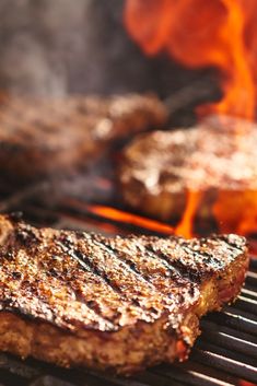 steaks cooking on the grill with flames coming out of it's back end