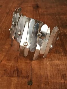 "You will love the way this fabulously unique cuff dresses up your wrist! The inside of this bracelet is a smooth silver band and the outside looks like it's had strips of silver hammered on. This looks like an artisan piece to me. The silver strips are anywhere from 1/2\" to 1 1/2\" long. Please bear in mind that silver is a fairly soft metal, and some of the strips are a bit bent in some areas, but I believe it takes away from the general look of the cuff. Please see all photos for details. I Silver Hammered Cuff Bracelet, Silver Hammered Metal Cuff Bracelet, Modern Hammered Metal Cuff Bracelet, Silver Hammered Cuff Bangle, Modern Metal Wide Band Bracelets, Modern Wide Band Metal Bracelet, Silver Metal Modernist Cuff Bracelet, Modern Sterling Silver Wide Band Bracelet, Modernist Silver Metal Cuff Bracelet