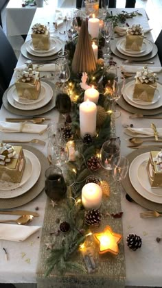 a table set for christmas with candles, plates and napkins on the place setting