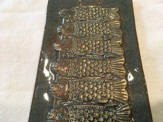 a metal plaque with fish on it sitting on top of a white cloth covered table