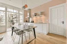 a dining room table and chairs in front of an open kitchen with lots of windows