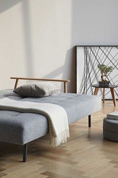 a bed sitting on top of a hard wood floor next to a chair and ottoman