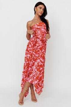 a woman wearing a red and pink floral print strapless dress with high low heels