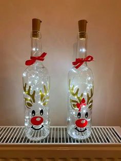 two glass bottles decorated with lights and reindeer heads