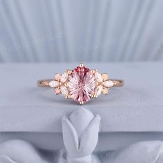 a pink diamond ring sitting on top of a white box