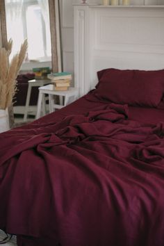 a bed with red sheets and pillows in front of a mirror