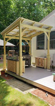 an outdoor kitchen and grill area in a backyard with wood decking, pergolated patio