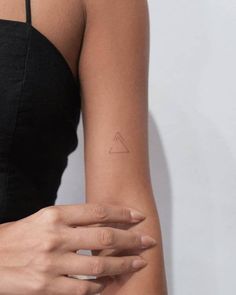 a woman's arm with a small triangle tattoo on the left side of her arm