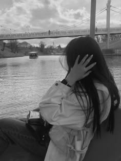 a woman sitting on the back of a boat in front of a bridge over water