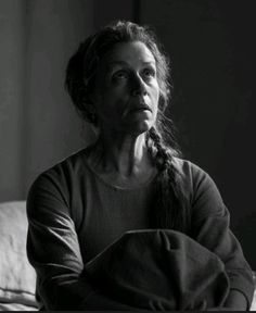 an older woman sitting on a couch with her hands in her pockets and looking off to the side