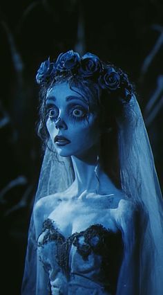 a woman dressed as corpse bride with blue makeup and flowers in her hair is staring at the camera