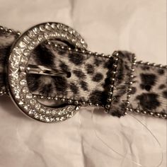 a leopard print belt with metal buckles and beads on the bottom, sitting on a white sheet