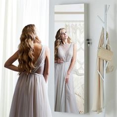 a woman standing in front of a mirror wearing a dress