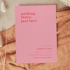 a pink card with the words nothing fancy just love on it sitting next to some dried flowers