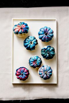 six blue and pink donuts on a white plate with a cloth napkin behind them