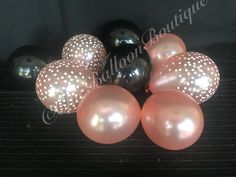 black and pink balloons with polka dots are arranged on a table in front of a black background