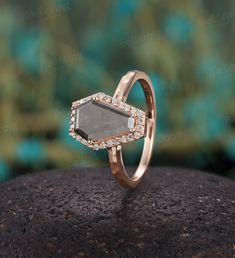 an engagement ring with a grey stone surrounded by white and brown diamonds on top of a rock