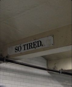 there is a sign that says so tired on the wall