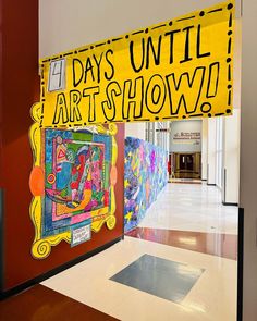 an art show is displayed on the wall in front of a large yellow sign that says days until art show