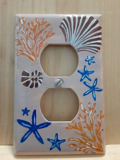 a decorative light switch plate with blue, orange and white sea stars on the bottom