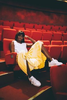 a woman is sitting in an empty theater seat with her legs up on the ground