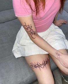 a woman sitting on top of a couch with tattoos on her leg and arm behind her head