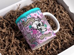 a coffee mug with a skull and roses on it sitting in some wood shavings