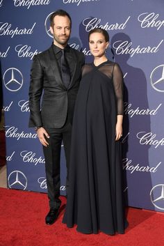 a man and woman standing next to each other on a red carpet at an event