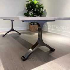 a white marble top dining table with black metal legs and a potted plant in the corner