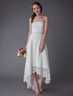 a woman in a strapless white dress holding a bouquet and posing for the camera