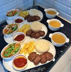 a table topped with plates of food and bowls of sauces on top of it