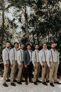 a group of men standing next to each other in front of some trees and snow