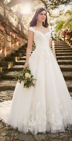 a woman in a wedding dress is standing on some stone steps and holding a bouquet