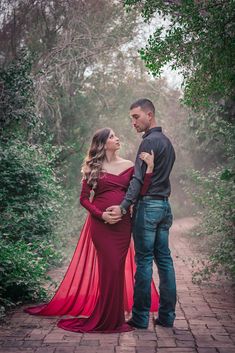 a man and woman standing next to each other on a brick walkway with trees in the background