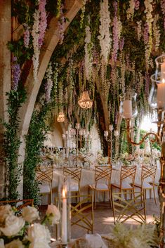 an elegant wedding reception with flowers and chandeliers hanging from the ceiling, surrounded by greenery