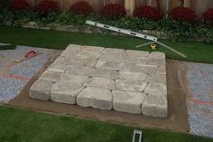 an outdoor patio being built with large rocks and grass in the back yard, surrounded by landscaping equipment