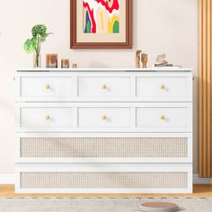 a white dresser sitting in a living room next to a painting