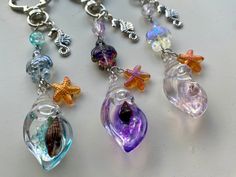 several different colored glass items hanging from a chain on a white counter top with silver accents