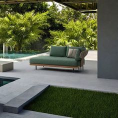 a couch sitting on top of a lush green field next to a swimming pool