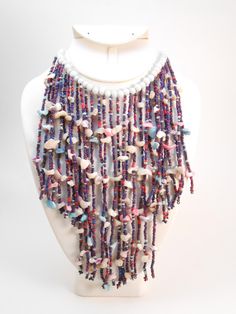 Here is an amazing tribal style bib necklace. Tiny purple/blue beads and wonderful delicate shells strung on a lovely light pale blue glass beads. This is an AMAZING necklace!!   See photos for more measurements. Handmade Purple Beaded Necklaces For Beach, Colorful Beaded Dangle Necklaces For Beach, Bohemian Shell Necklace With Gemstone Beads, Bohemian Multicolor Beaded Shell Necklace, Handmade Bohemian Bib Necklaces For The Beach, Handmade Bohemian Bib Necklace For Beach, Festival Shell Necklaces With Colorful Beads, Festival Necklaces With Colorful Shell Beads, Festival Shell Necklace With Colorful Beads