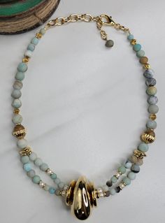 Our River necklace is handmade with amazonite beads which are known for their soothing properties. A few natural freshwater pearls are sprinkled among the blue amazonite beads. The River necklace features a vintage Italian gold plated bead that is like a stone shaped by moving water, smooth and inviting. This gorgeous statement piece is handmade in the United States. A coordinating bracelet and set of earrings is available. Features: - Italian Vintage Elements from 1980s - Gold Plated Cable Chai Elegant Amazonite Bead Necklaces, Elegant Amazonite Beaded Necklace, Polished Amazonite Round Bead Necklaces, Amazonite Polished Round Bead Necklaces, Elegant Handmade Amazonite Beaded Necklace, Handmade Amazonite Round Beads Necklaces, Gift Amazonite Beaded Necklace With Polished Beads, Artisan Amazonite Round Bead Necklace, Adjustable Amazonite Necklace With Polished Beads